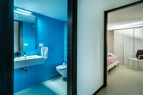 a blue bathroom with a toilet and a sink at Fly Home Sicily in Marina di Ragusa