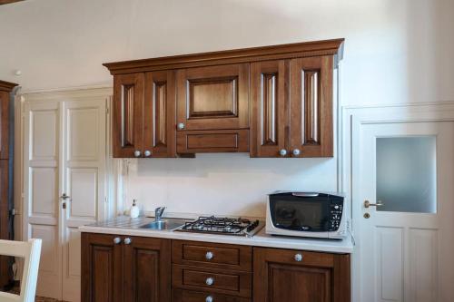 a kitchen with wooden cabinets and a sink and a microwave at Al Duomo in Lonato del Garda