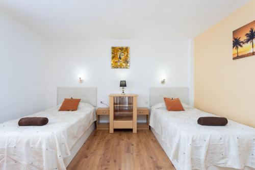 エル・メダノにあるApartamento Centro El Médanoの白い壁とウッドフロアの客室で、ベッド2台が備わります。