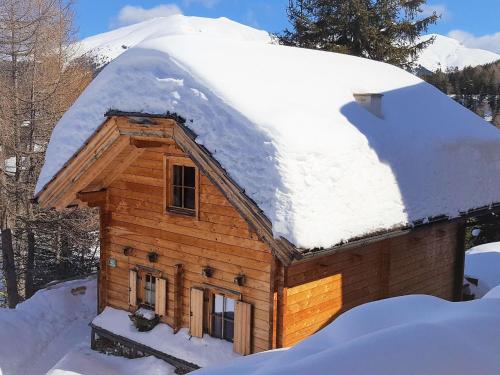 uma cabana de madeira com um telhado coberto de neve em Ski in ski out chalet on the Turracher Hoehe em Turracher Höhe