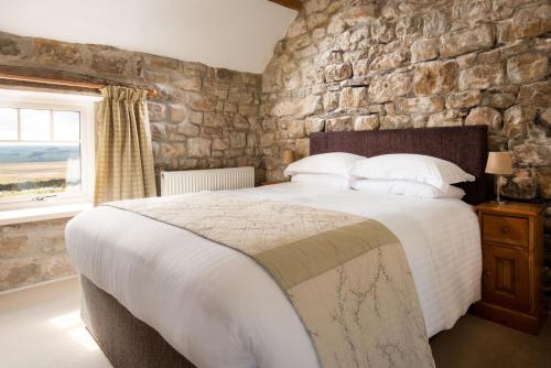 a bedroom with a large bed and a stone wall at Shepherds Retreat in Hexham