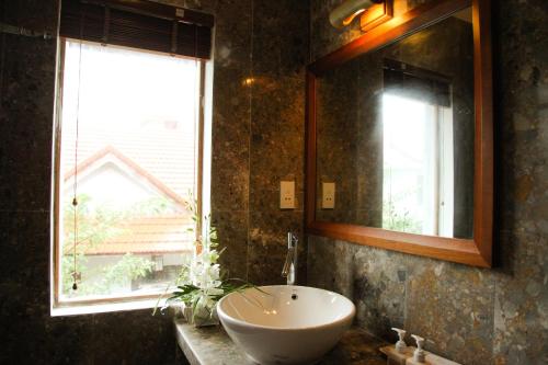 baño con lavabo, espejo y ventana en Charming Homestay, en Hoi An