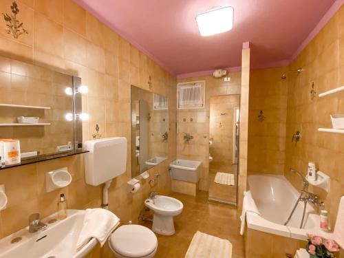 a bathroom with a toilet and a tub and a sink at Sole 4 Garten Ferienwohnung mit Pool EG in Colico