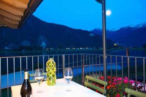 a table with two glasses of wine on a balcony at Dascio Silence Ferienwohnung mit Panorama Balkon in Dascio