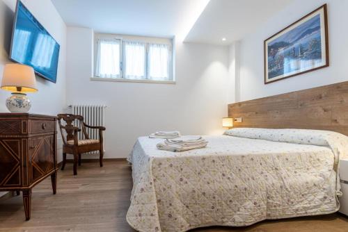 een slaapkamer met een bed, een tafel en een stoel bij Fiori Pool-Gartenwohnung (EG) in Colico