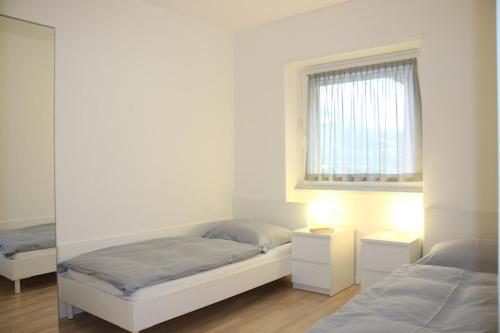 een witte kamer met 2 bedden en een raam bij Rose Gialla Pastella Terrassen Ferienwohnung OG in Colico