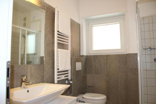 een badkamer met een wastafel, een toilet en een raam bij Rose Gialla Pastella Terrassen Ferienwohnung OG in Colico