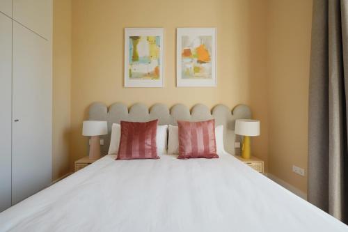 sypialnia z białym łóżkiem z 2 czerwonymi poduszkami w obiekcie numa I Prestigio Apartments w Sewilli