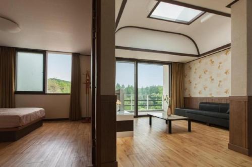 a bedroom with a bed and a couch and windows at Berion Reosrt in Pyeongchang