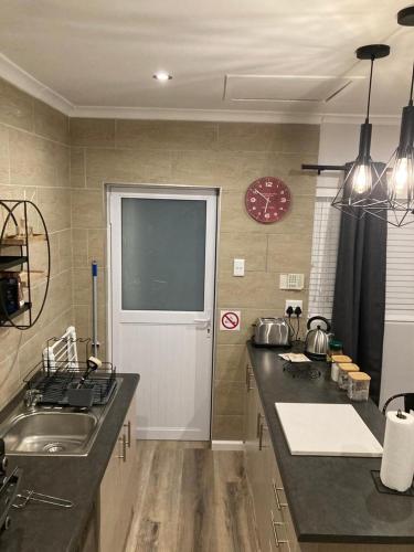 a kitchen with a sink and a counter with a window at Leafy Retreat Kenridge Trendy in Durbanville