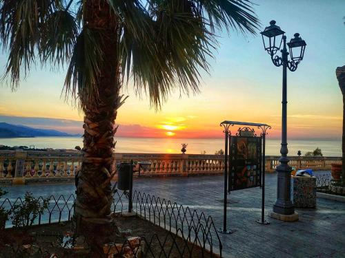 a palm tree and a street light with the sunset at THE PALACE B&B and Apartments in Santo Stefano di Camastra
