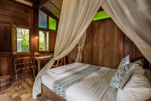 a bedroom with a canopy bed with a desk and windows at Yabbiekayu in Yogyakarta