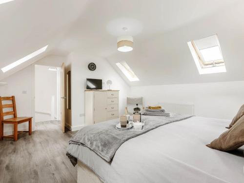 a white bedroom with a bed and a chair at Lilac Lodge in Flaxley