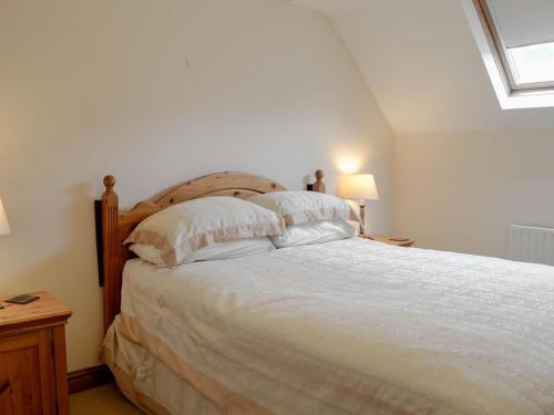 1 dormitorio con 1 cama grande con sábanas y almohadas blancas en Bridge Street Close, en Cockermouth