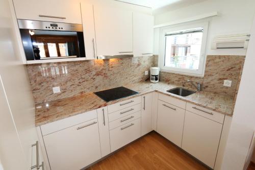 a kitchen with white cabinets and a sink and a window at Chalet La Sapinière in Saas-Fee