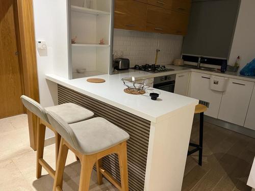 uma cozinha com um balcão branco e algumas cadeiras em Superbe Appartement kantaoui sousse em Sousse