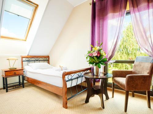 ein Schlafzimmer mit einem Bett, einem Stuhl und einem Fenster in der Unterkunft Hotel Wartosław in Wronke