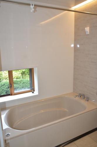a white bath tub in a bathroom with a window at Auberge Fujii Fermier in Fukui