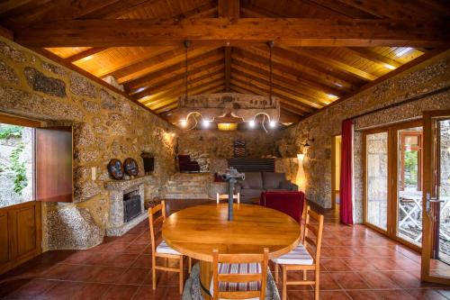 a dining room with a wooden table and a fireplace at Gerês Country Stays - Lagar in Rio Caldo