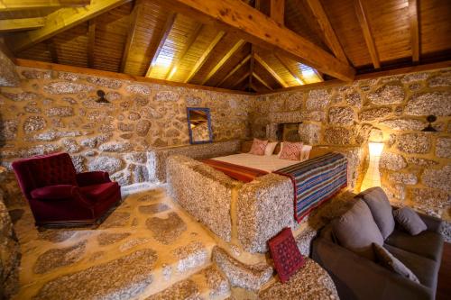 a room with a bed and a couch in a stone wall at Gerês Country Stays - Lagar in Rio Caldo