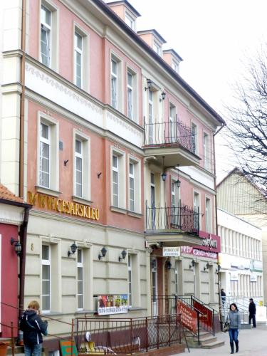 a building on a street with people walking in front of it at Hotel Cesarski - Kaiserhof in Giżycko