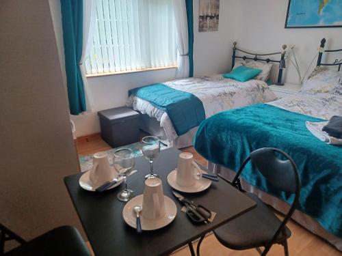 una habitación con 2 camas y una mesa con copas de vino en Loughview Retreat in the Mournes en Newcastle