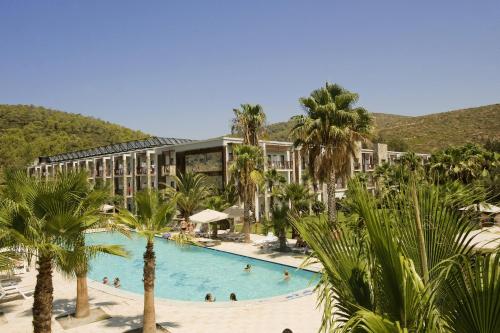 a resort with a large swimming pool with palm trees at Green Bay Resort & Spa - All Inclusive in Guvercinlik