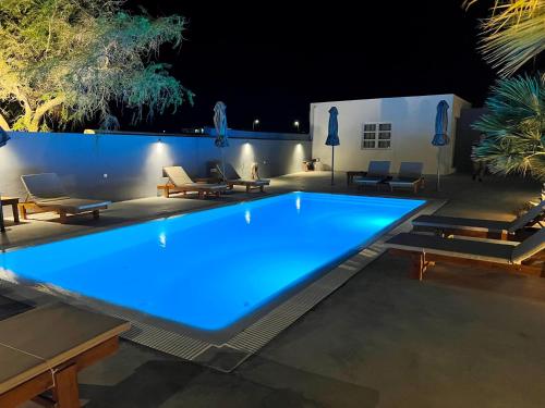 una gran piscina con luces azules en un patio por la noche en White Lily Santorini - Adults Only 16 Plus en Perivolos