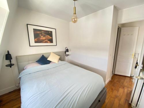 ein Schlafzimmer mit einem großen weißen Bett mit blauen Kissen in der Unterkunft Lumineux, Parc Monceau, Champs Elysées, Sacré Coeur in Paris