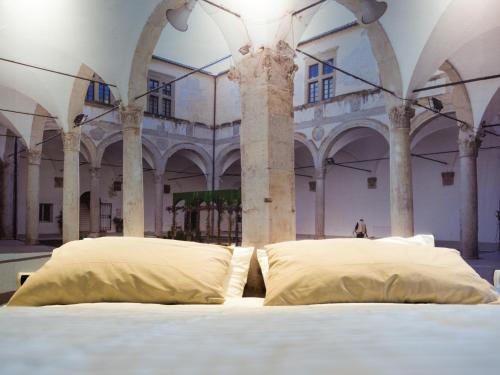 1 cama con 2 almohadas en una habitación con columnas en Alla scoperta delle Marche, en Camerino