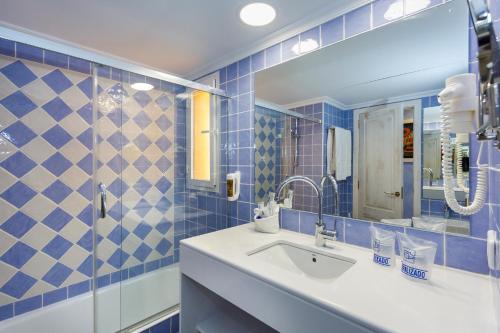 Baño de azulejos azules con lavabo y espejo en Royal Son Bou Family Club en Son Bou