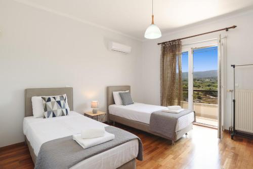 a bedroom with two beds and a large window at Villa Amarandes by Villa Plus in Paradeísion