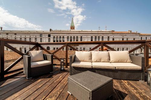 a balcony with two chairs and a table and a building at Ca' Algi - Luxury San Marco View in Venice