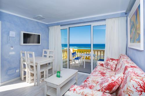een woonkamer met een bank en uitzicht op de oceaan bij Royal Son Bou Family Club in Son Bou
