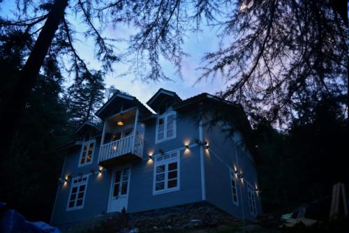 uma casa azul com luzes à noite em Woodzo Shangarh em Sainj