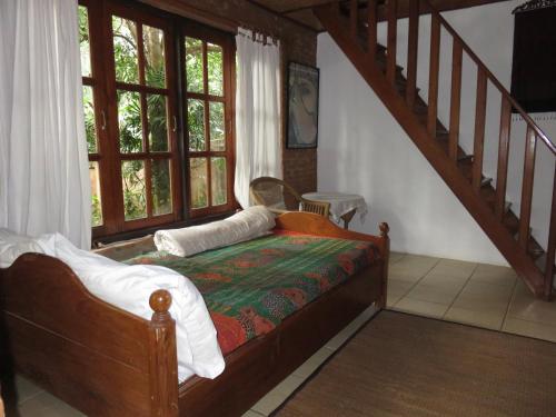 a bedroom with a bed and a staircase with windows at Little Eden Guesthouse in Pang Mapha
