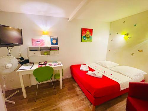 um pequeno quarto com uma cama vermelha e uma secretária em La petite Maison dans la Croix Rousse em Lyon