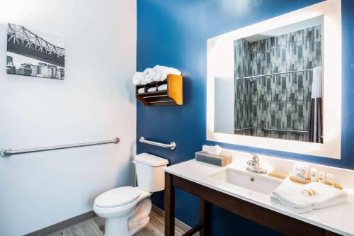a bathroom with a toilet a sink and a mirror at La Quinta Long Island City in Queens