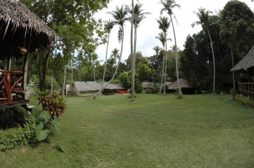 a large yard with palm trees and a building at Paradise Lost Bungalows in Koh Kradan