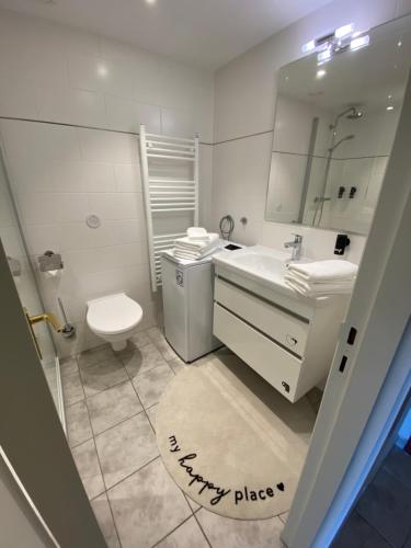een badkamer met een wastafel, een toilet en een spiegel bij Timmendomizil - schöne Ferienwohnung in bester Lage - Sonnenseite in Timmendorfer Strand