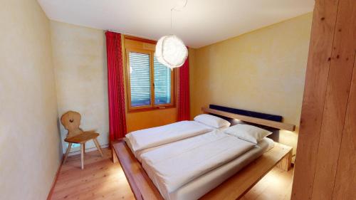a bedroom with a bed and a chair and a window at Chalcherin Duplex in Celerina