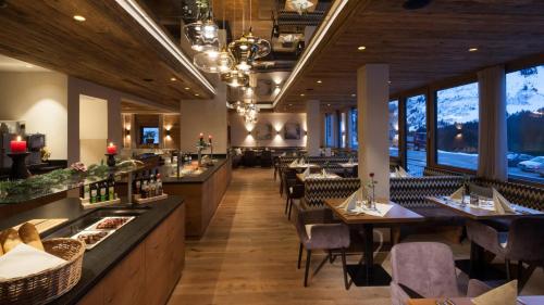 ein Restaurant mit Tischen, Stühlen und Fenstern in der Unterkunft Das alpine Lifestyle Berghotel Madlener in Damüls
