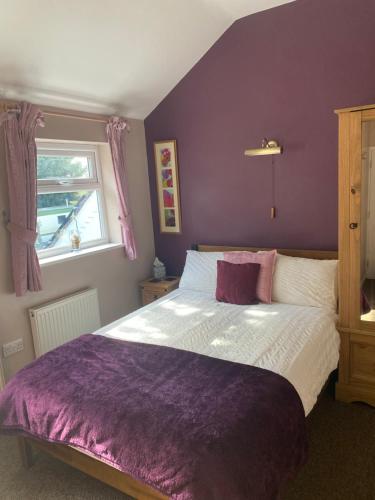 a purple bedroom with a bed and a window at White Heather Guest House in Mablethorpe