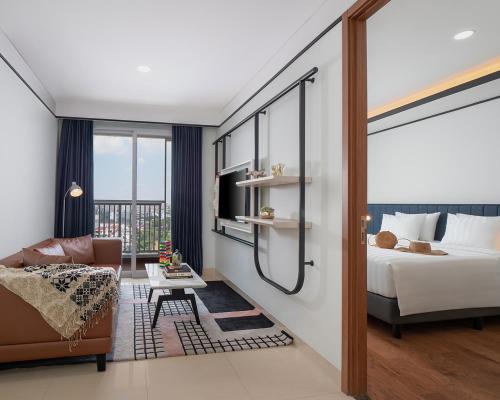 a bedroom with a bed and a living room with a couch at The Reiz Suites, ARTOTEL Curated in Medan