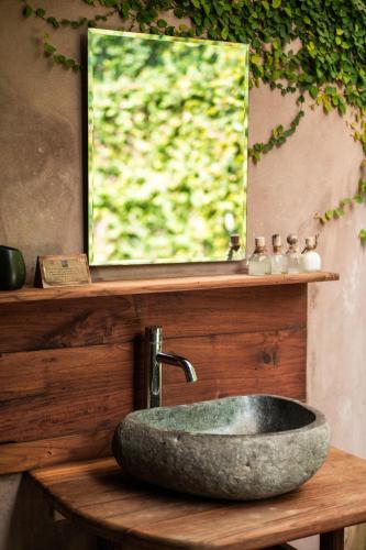 a stone sink on a wooden counter with a mirror at Yabbiekayu in Yogyakarta