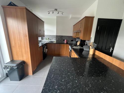 a large kitchen with wooden cabinets and a black counter top at Royston Village, Barnsley, 1930’s contemporary villa in Royston