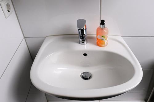 a white sink in a bathroom with a bottle of soap at Haus Magdalene in Bad Schwartau