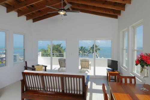 a dining room with a table and chairs and the ocean at Weezie's Ocean Front Hotel and Garden Cottages in Caye Caulker