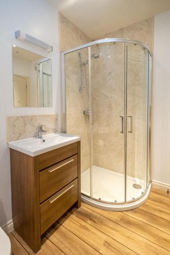 a bathroom with a shower with a sink and a mirror at 2 King Georges - Aldeburgh Coastal Cottages in Aldeburgh