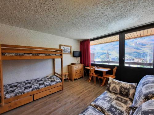 - une chambre avec 2 lits superposés, une table et un bureau dans l'établissement Studio Confort pour 3 avec Balcon Sud, Pied des Pistes, Animaux Acceptés - FR-1-452-289, aux Menuires